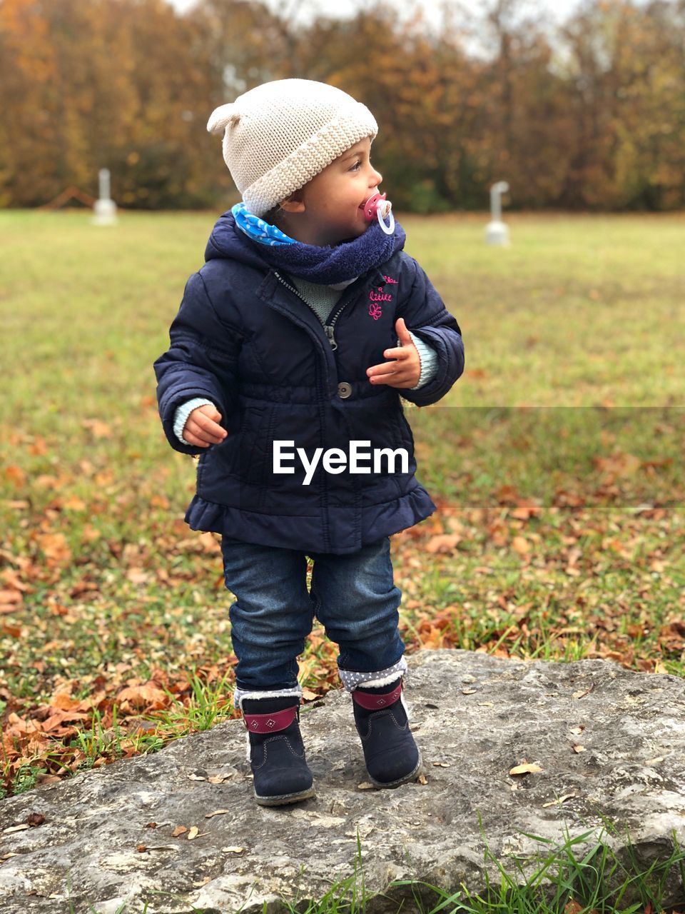 Girl sucking pacifier while standing on rock