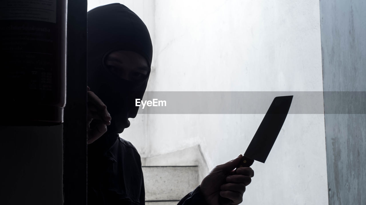 Robber holding knife while peeking through door