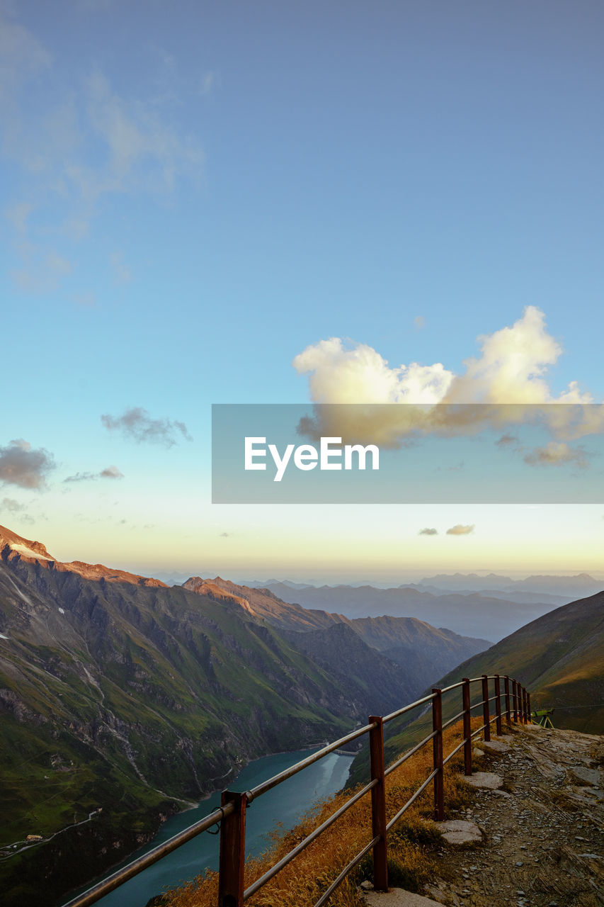 sky, scenics - nature, cloud, environment, mountain, morning, landscape, beauty in nature, nature, railing, sunlight, tranquil scene, tranquility, horizon, mountain range, no people, non-urban scene, travel, fence, travel destinations, land, idyllic, outdoors, architecture, tourism, sea, sunrise, water, blue, day, dusk, built structure, reflection