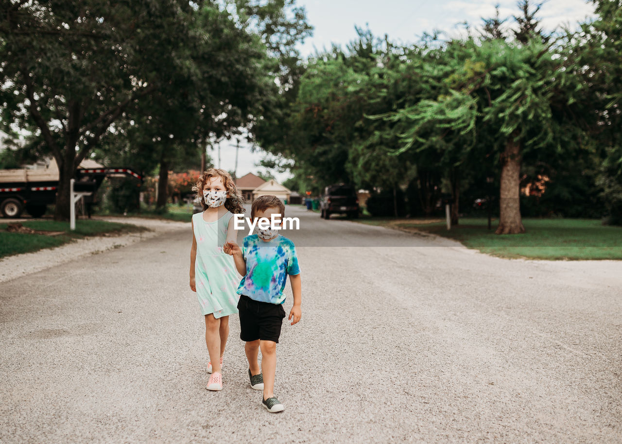 Young kids walking down street together wearing homemade masks