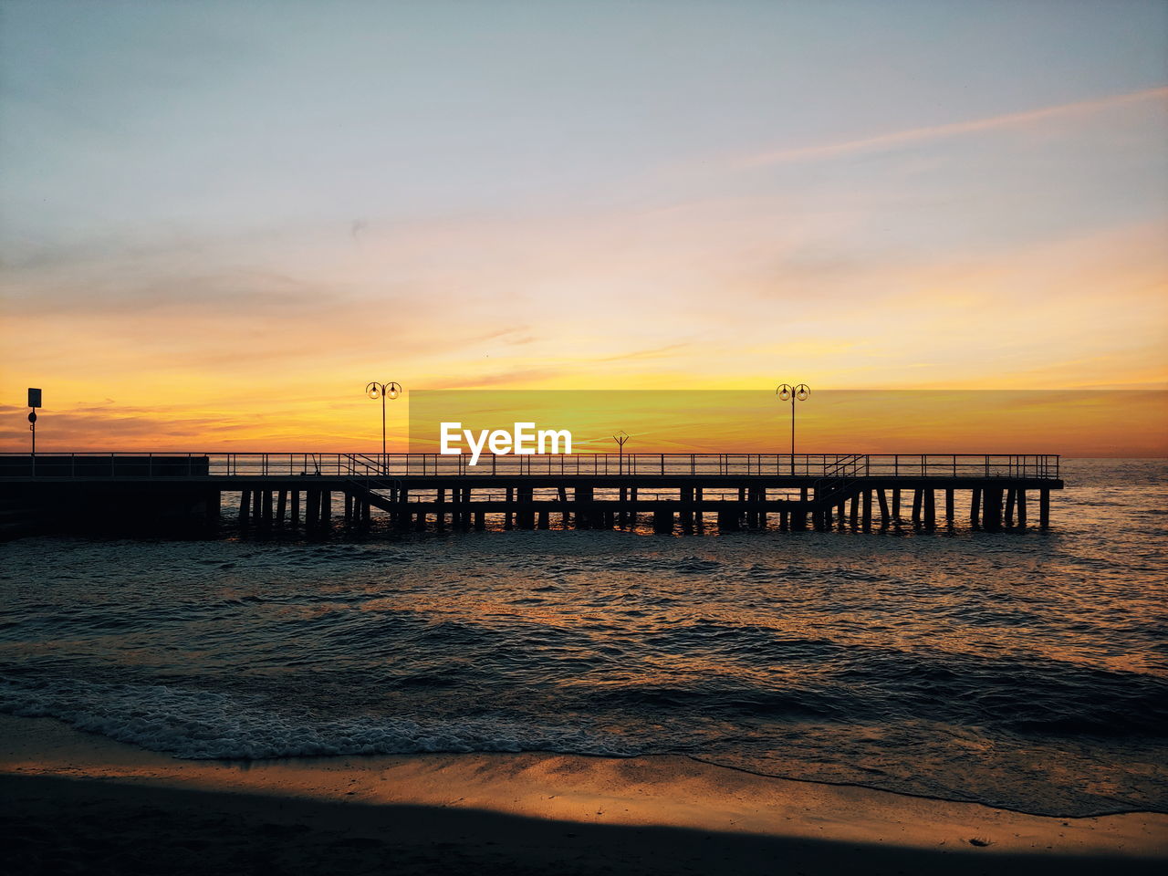 PIER ON BEACH AGAINST SKY DURING SUNSET