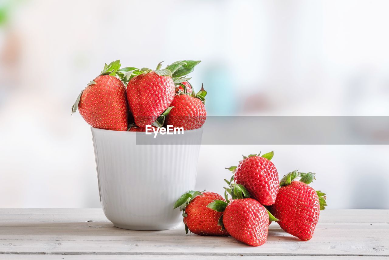CLOSE-UP OF FRESH STRAWBERRIES ON TABLE IN PLATE