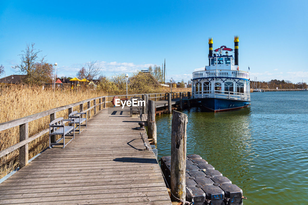 water, waterway, sea, sky, walkway, nature, transportation, architecture, vacation, pier, coast, boardwalk, nautical vessel, wood, clear sky, dock, ship, travel destinations, built structure, vehicle, day, travel, mode of transportation, boat, blue, channel, outdoors, sunny, harbor, shore, no people, sunlight, body of water, jetty, tourism, landscape, bridge, watercraft, land, scenics - nature, canal, tranquility
