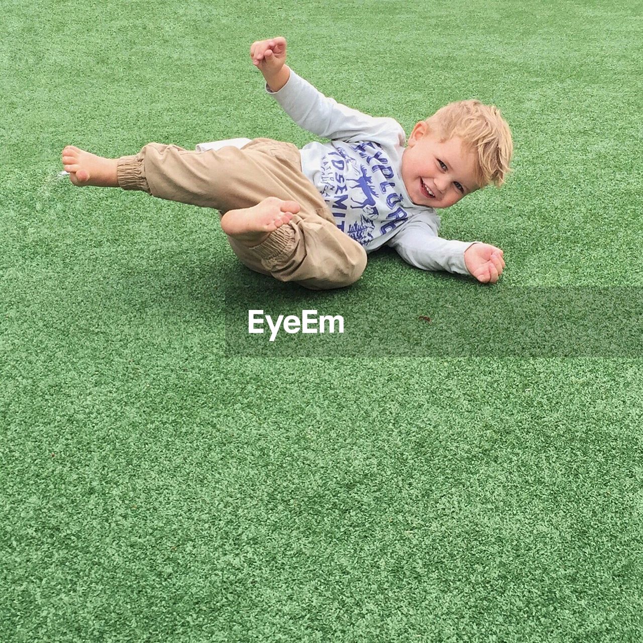 LITTLE BOY PLAYING IN GRASSY FIELD