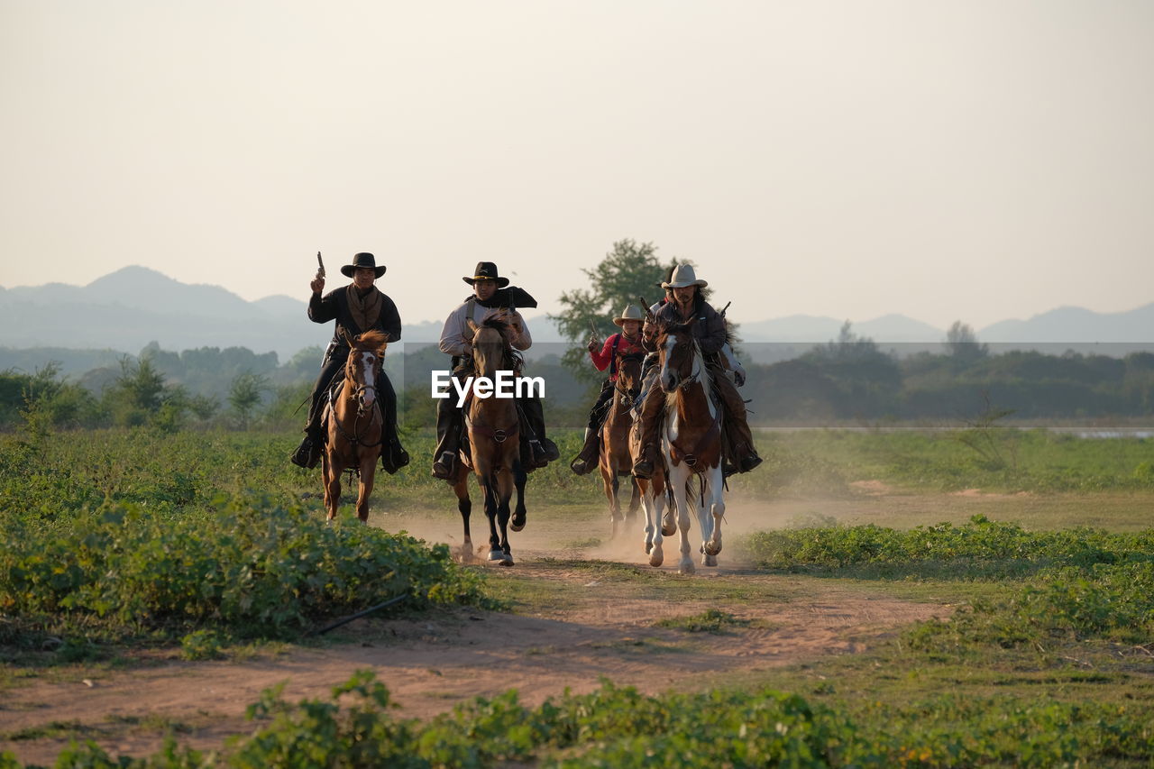 PEOPLE RIDING HORSES ON FIELD