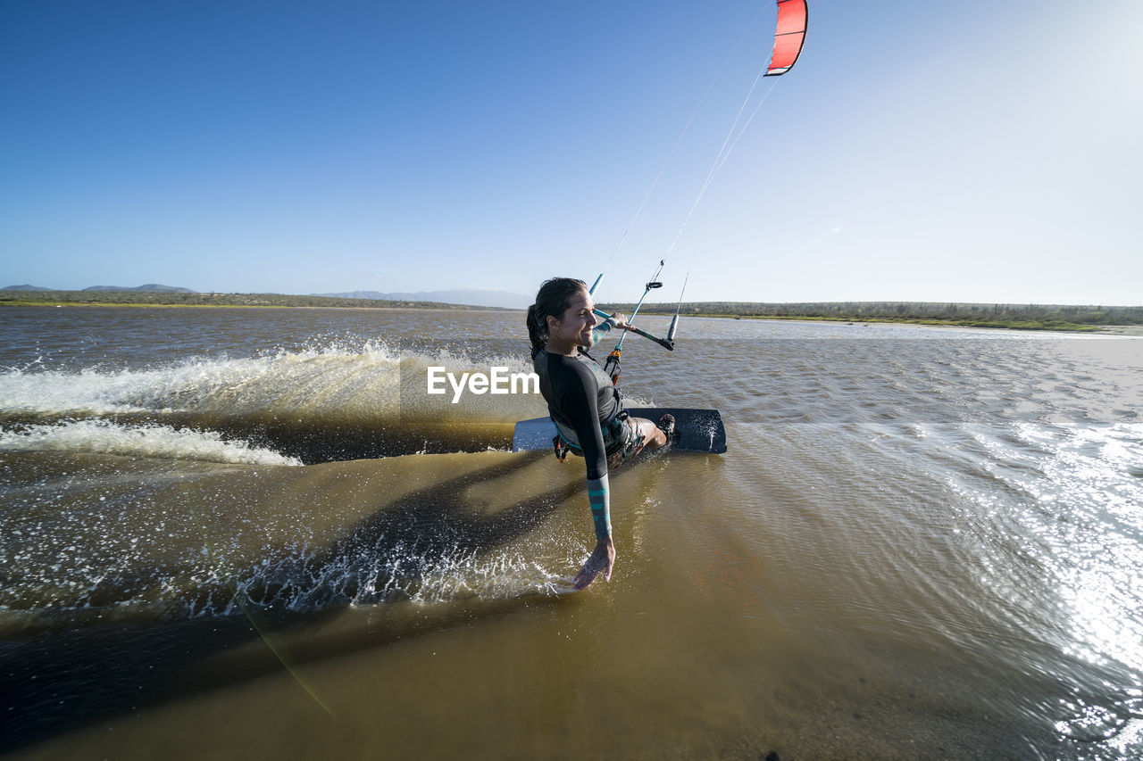 Happy female kiteboarder skims the water with her hand in mexico