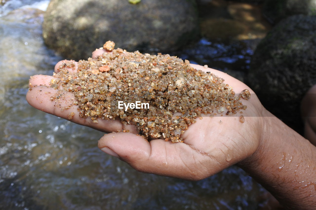 Cropped hand of man holding wet gravel