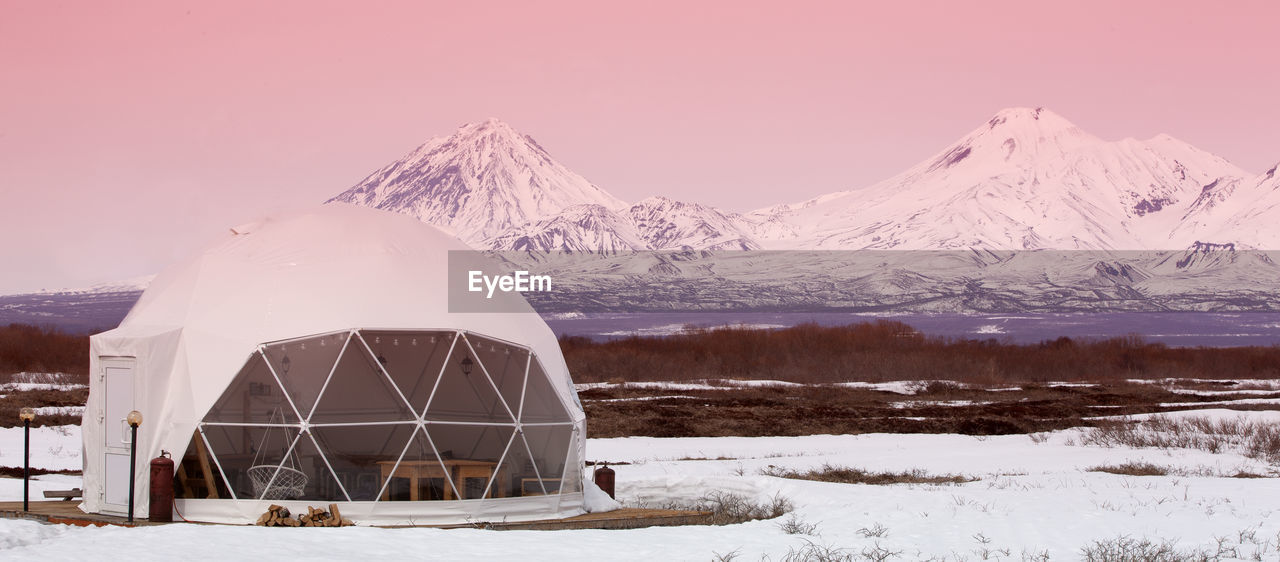 Glamping house and volcano, rural landscape, tent houses in kamchatka peninsula. selective focus.