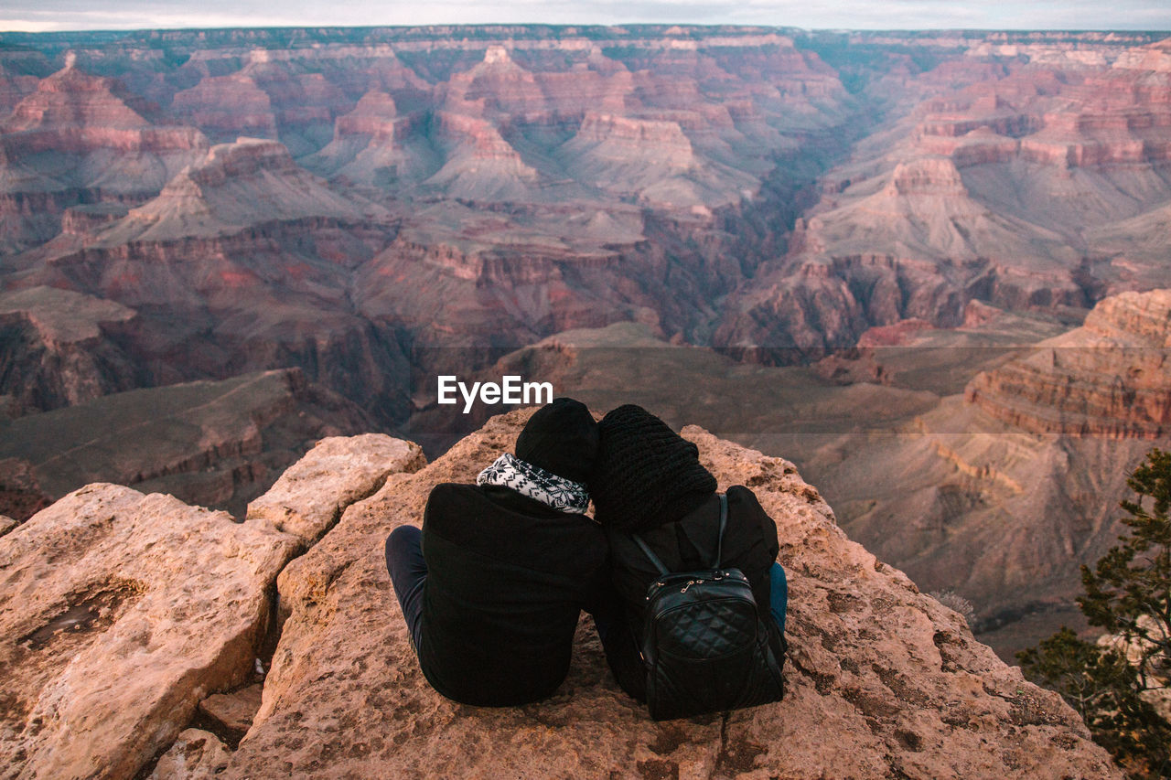 Rear view of couple sitting on rock formation at grand canyon national park