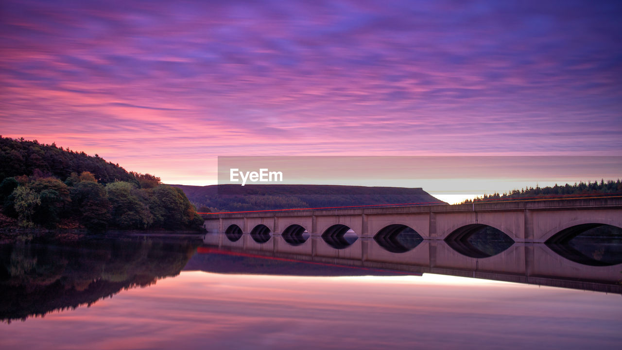 Bridge over river against sky during sunrise