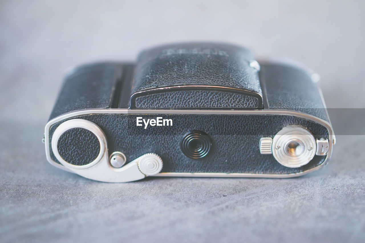 HIGH ANGLE VIEW OF CAMERA ON TABLE AGAINST WHITE BACKGROUND