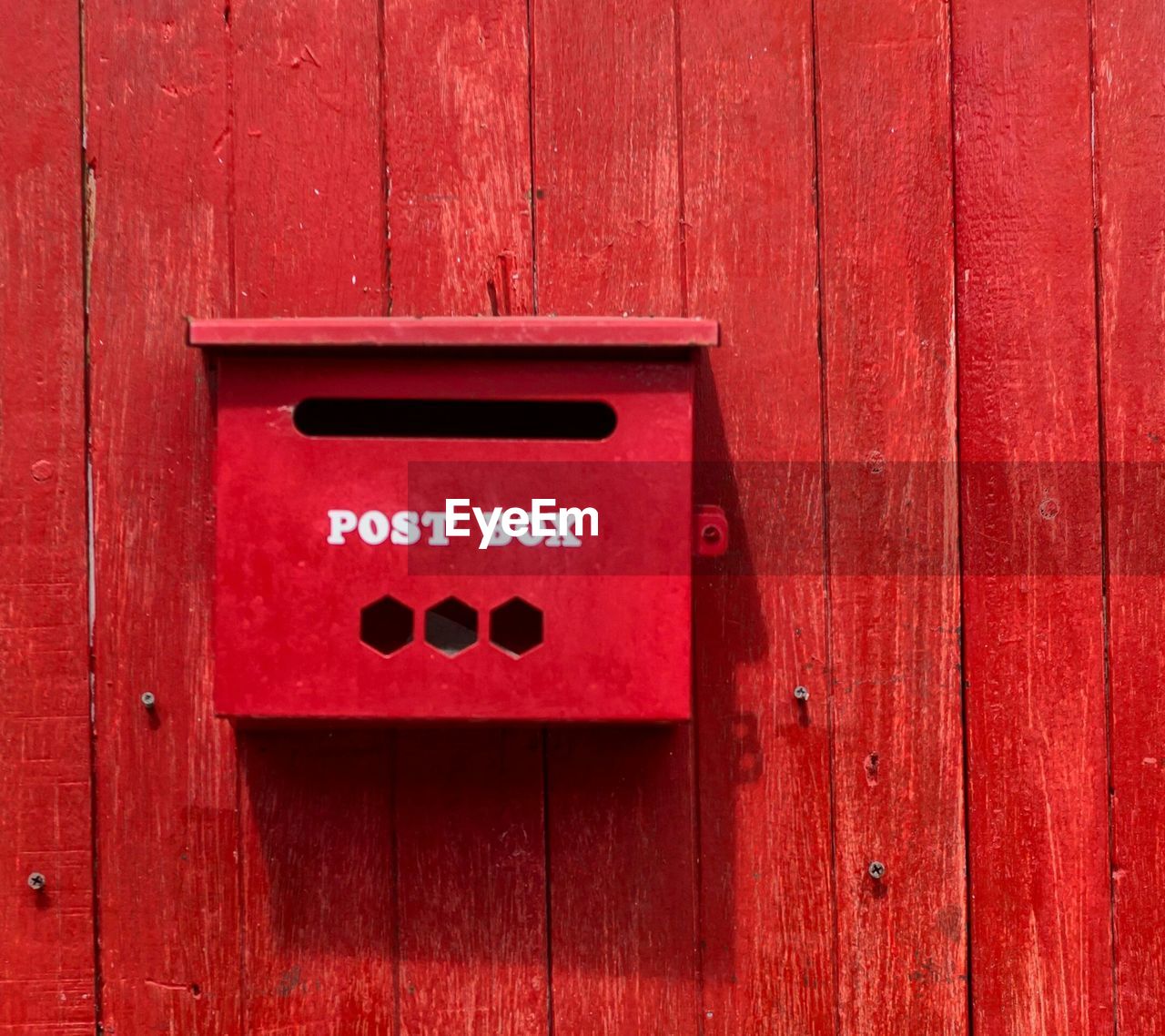 Red post box on wooden wall