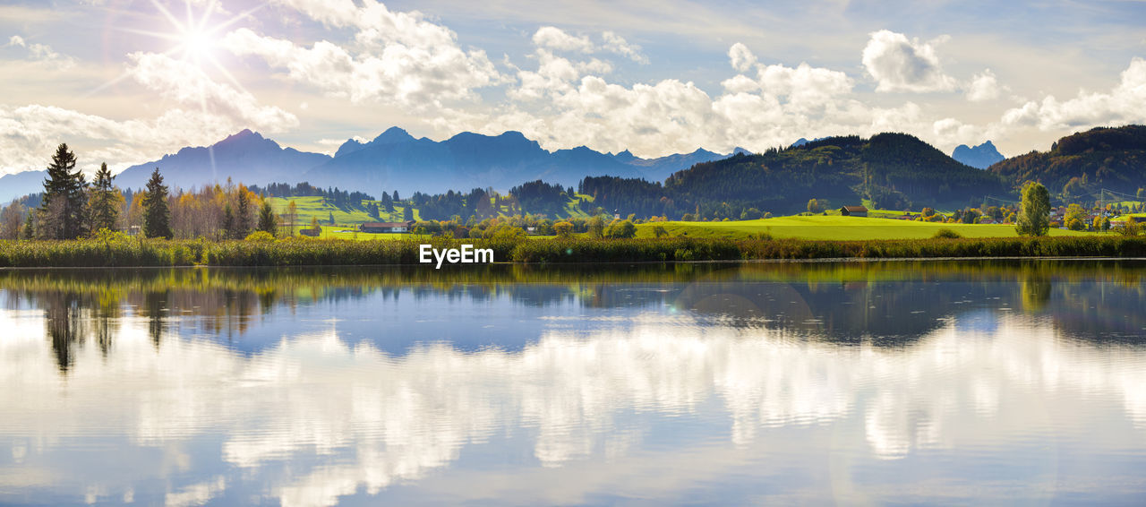 Wide angle view to alps mountain range mirroring in lake forggensee in region allgaeu in bavaria