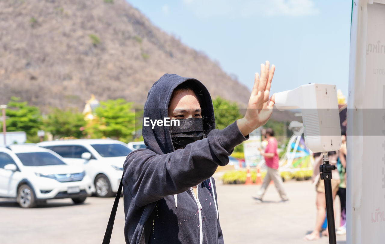 Yong woman using infrared digital thermometer measurement with palm measuring fever at checkpoint 