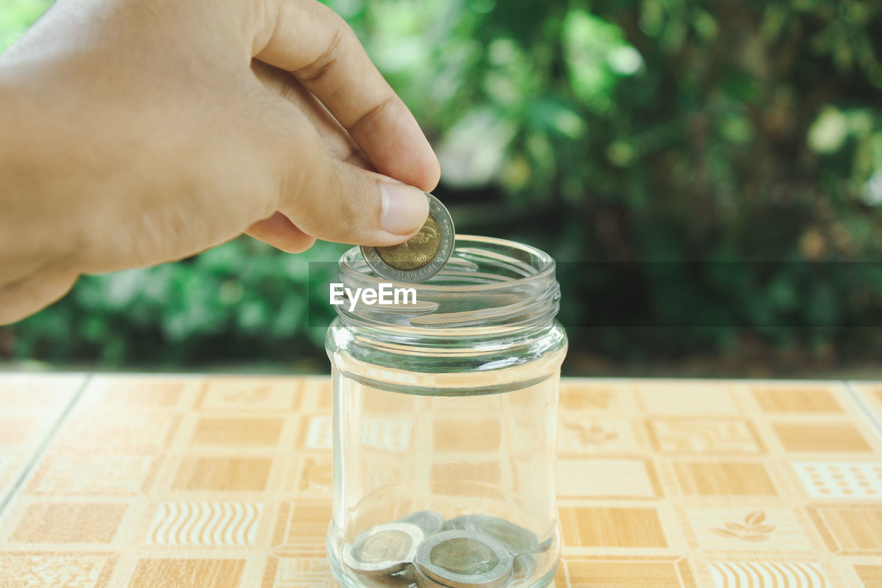 CLOSE-UP OF PERSON HOLDING GLASS JAR