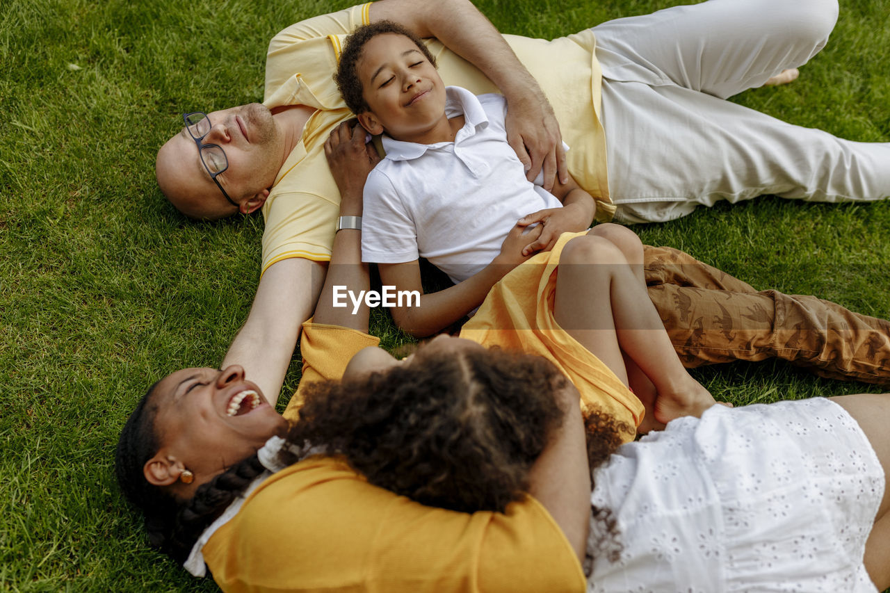 Happy woman with man and children lying on grass