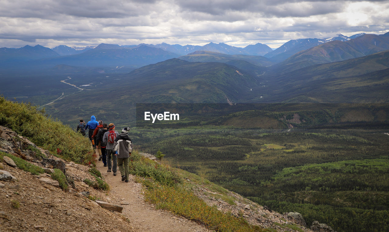 Rear view of people walking on mountain road