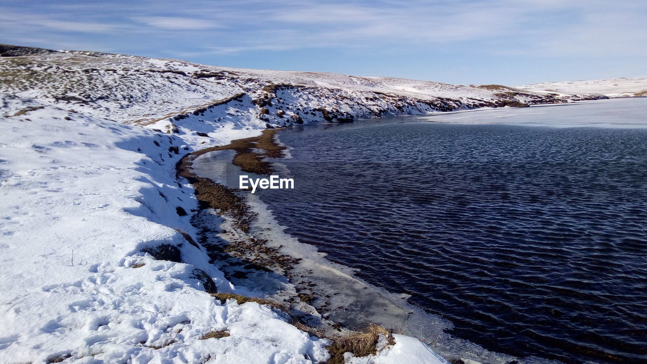 Partly frozen lake up the waterfall in iceland