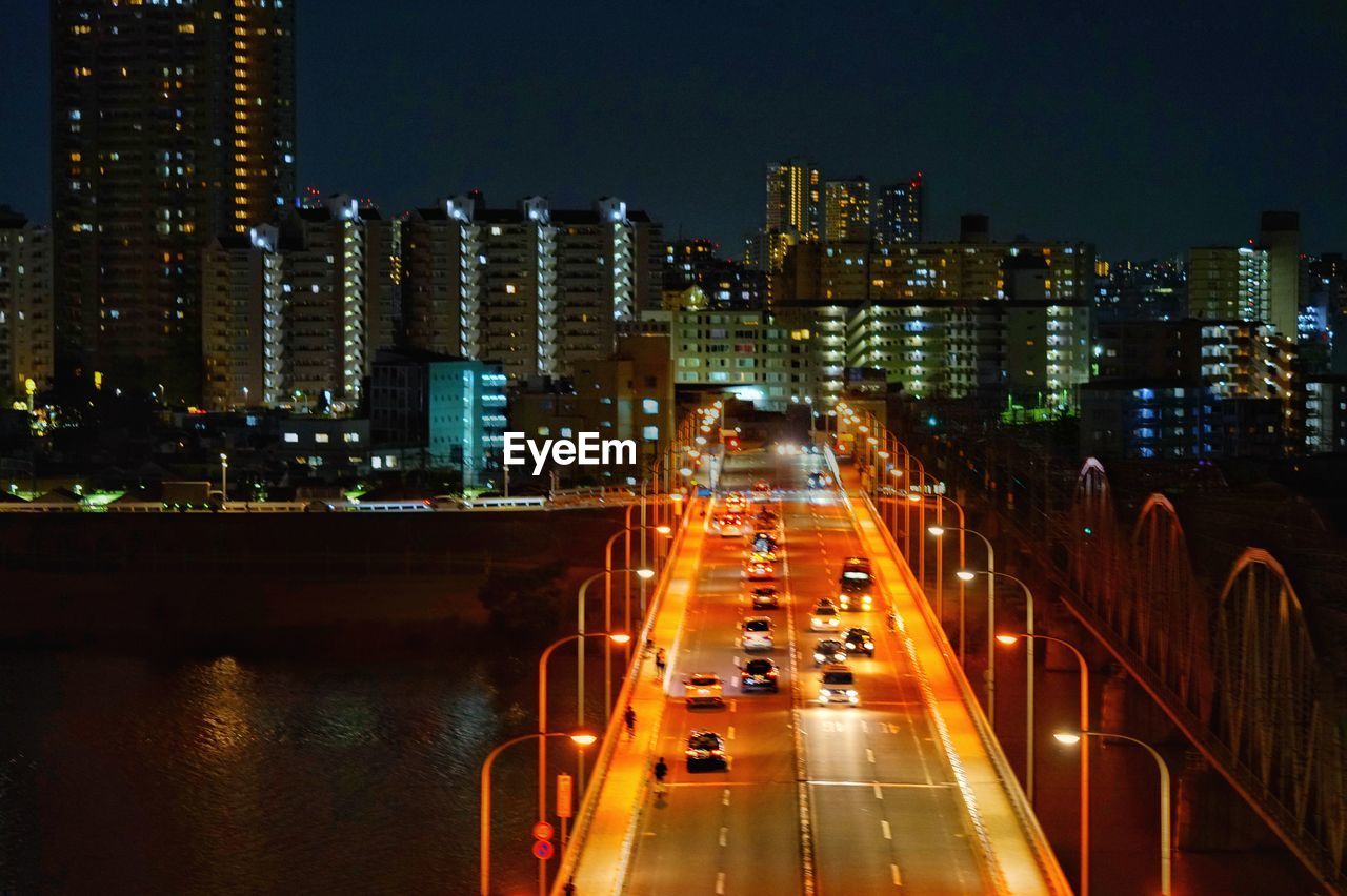 ILLUMINATED CITY STREET AMIDST BUILDINGS AT NIGHT