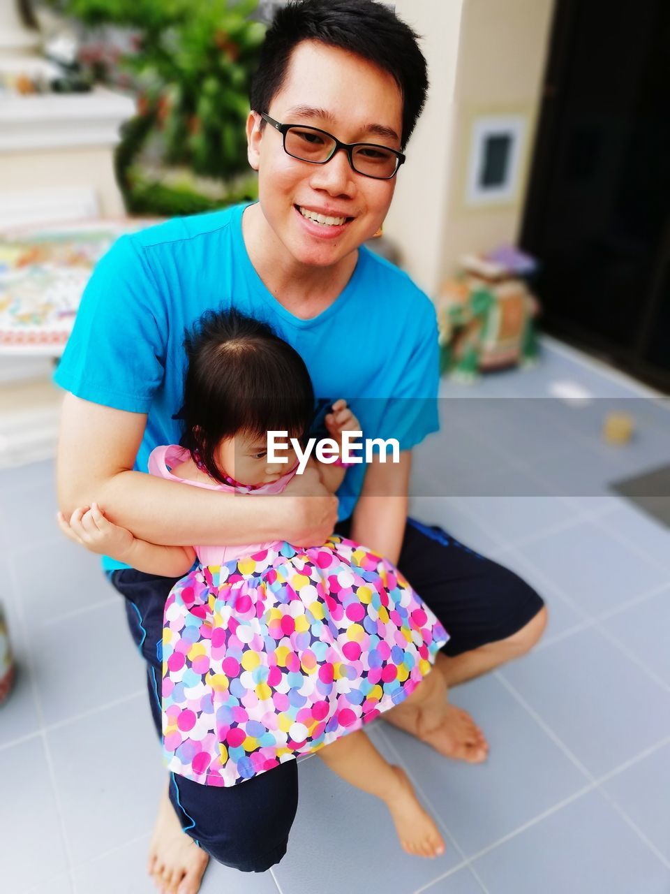 High angle view of father holding cute daughter while sitting outdoors