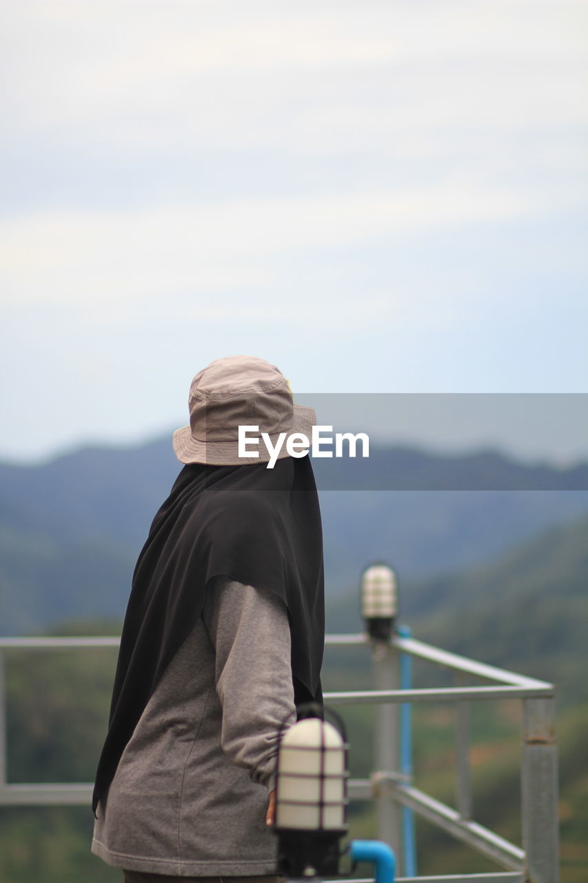 Side view of woman standing by railing against mountain