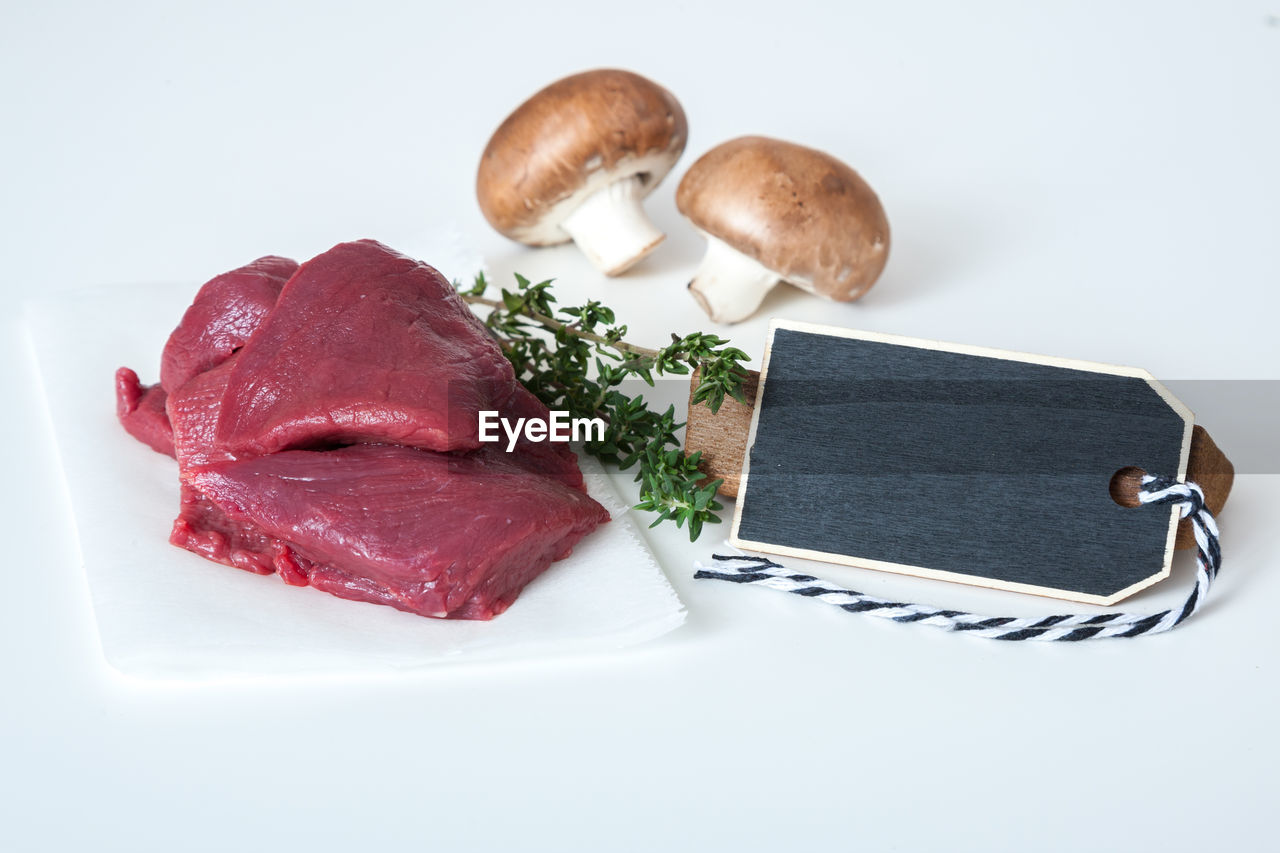 Close-up of meat on paper against white background