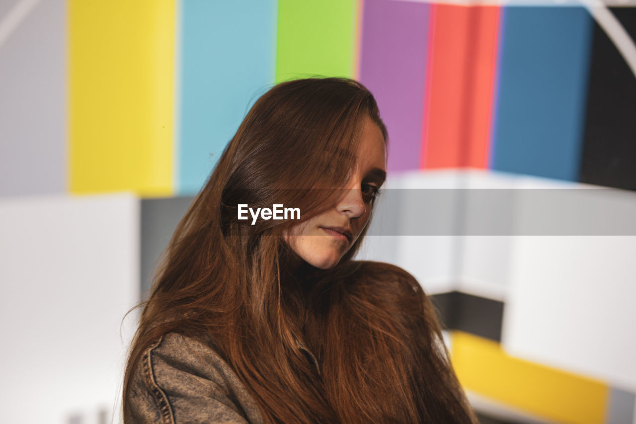 Portrait of young woman against multi colored wall