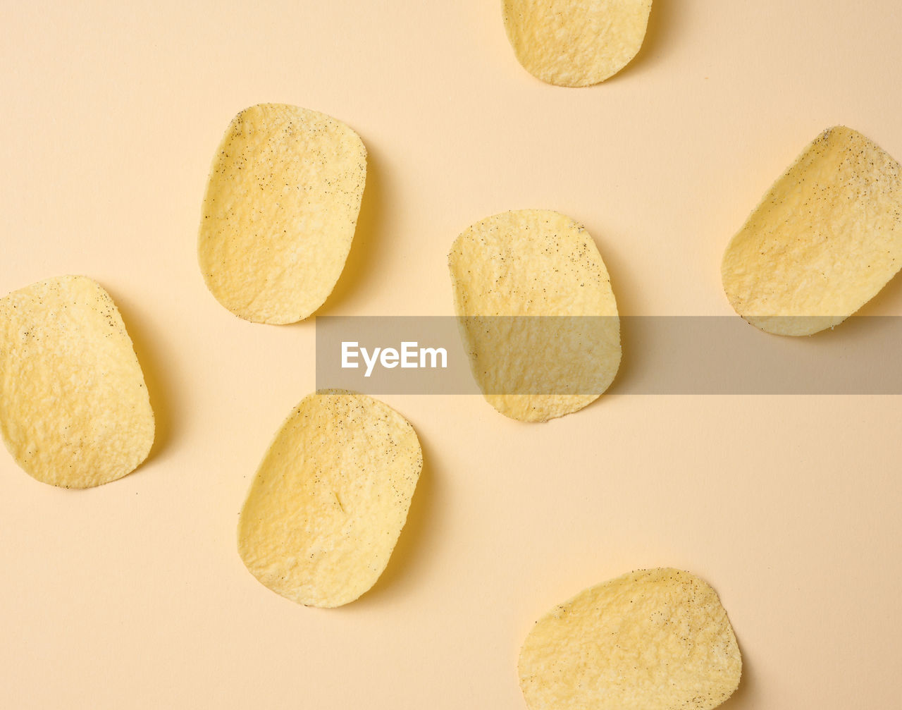 Round potato chips on a beige background, top view