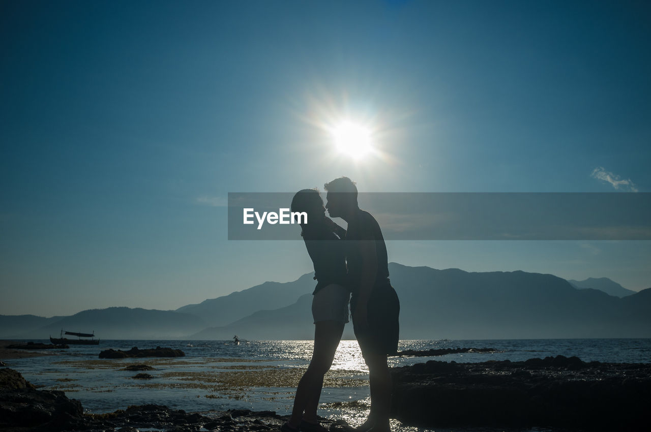 Side view of silhouette couple standing against sky