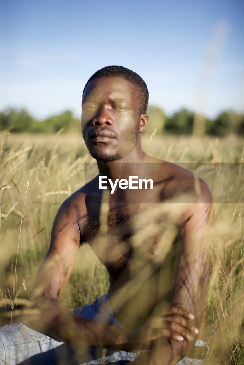 Portrait of young man sitting on field