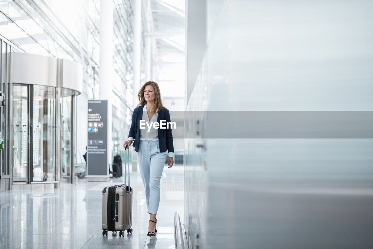 Young businesswoman walking with luggage at the airport