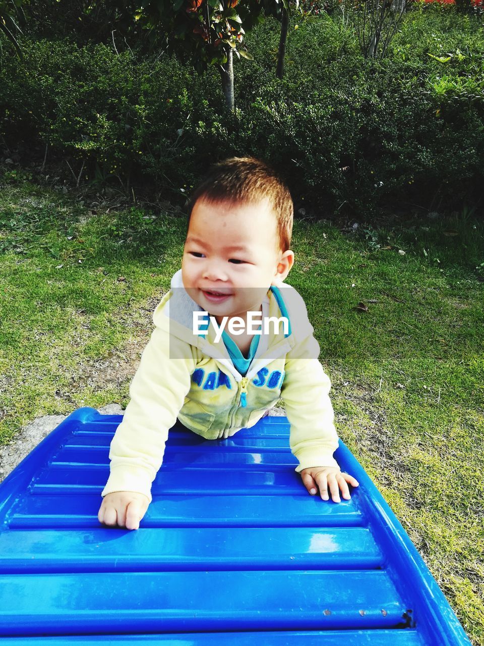 Cute baby boy playing on play equipment at park