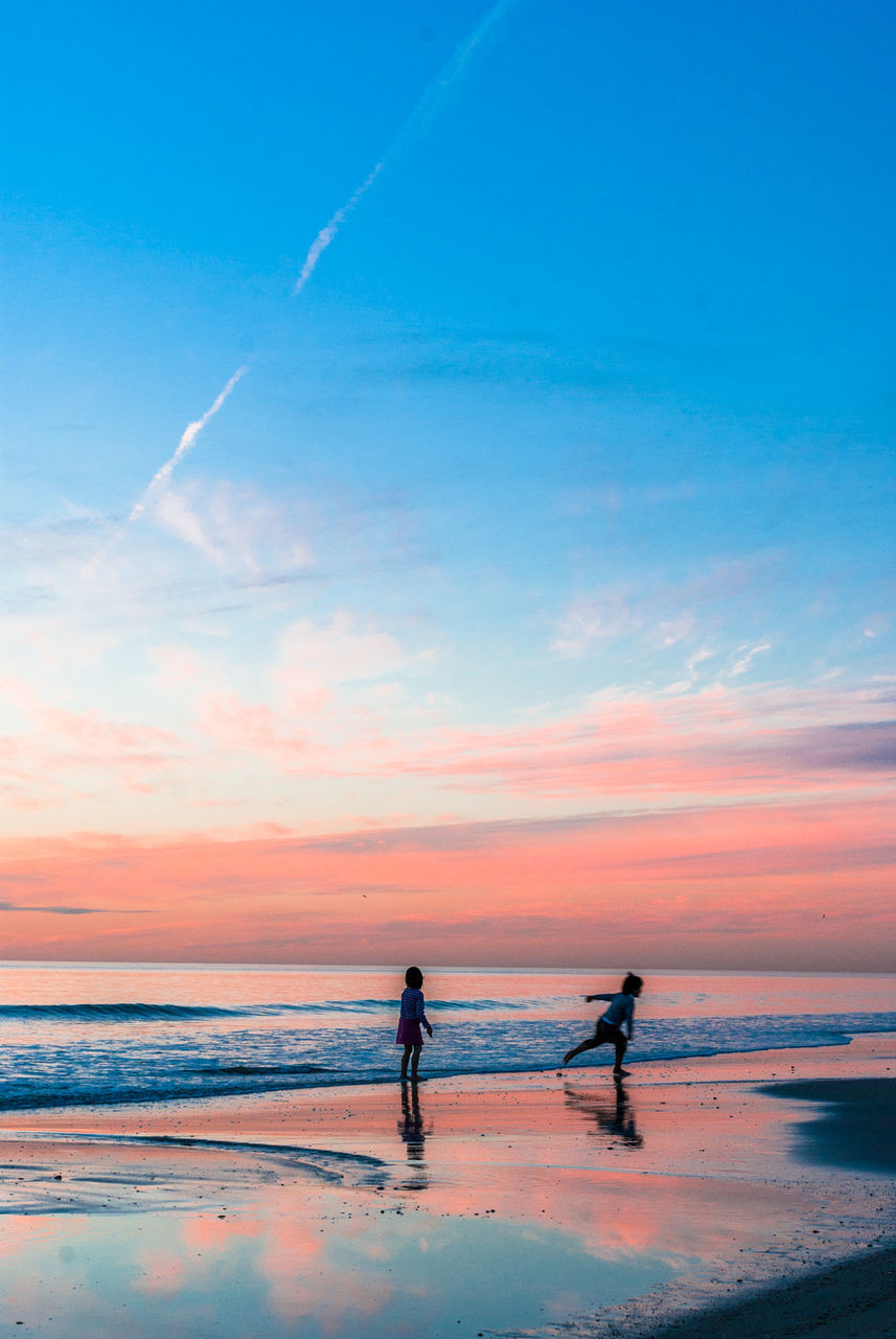 SILHOUETTE MAN STANDING ON BEACH AGAINST SKY DURING SUNSET