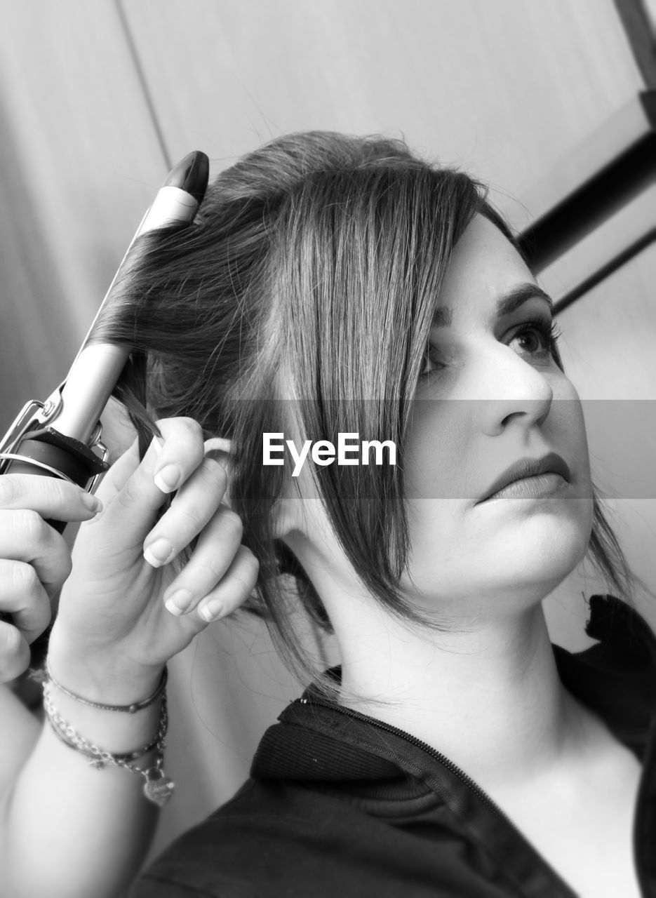 Cropped hands of beautician styling woman hair