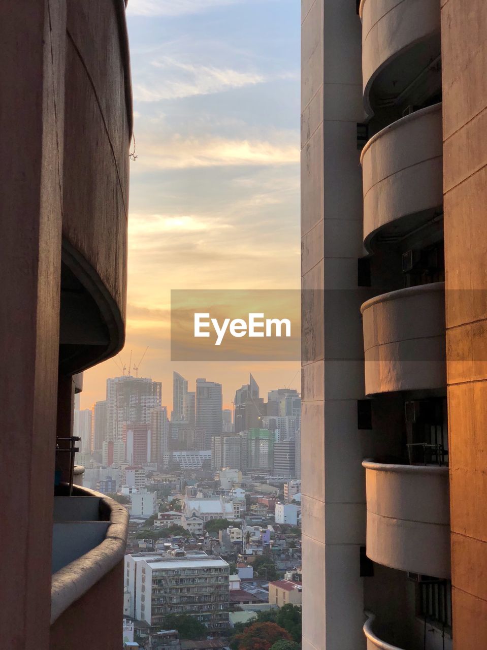 Modern buildings in city against sky during sunset