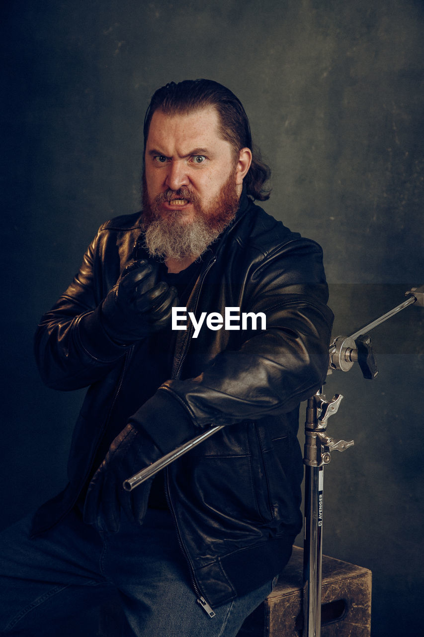 adult, one person, men, beard, facial hair, portrait, person, musician, looking at camera, mature adult, clothing, darkness, indoors, weapon, studio shot, human face, serious, occupation, jacket