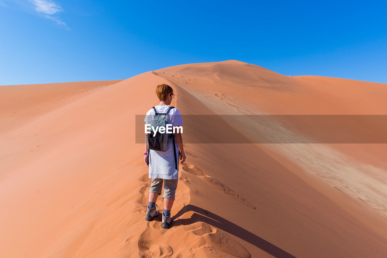 Rear view of female tourist standing at namib desert in naukluft national park during sunny day