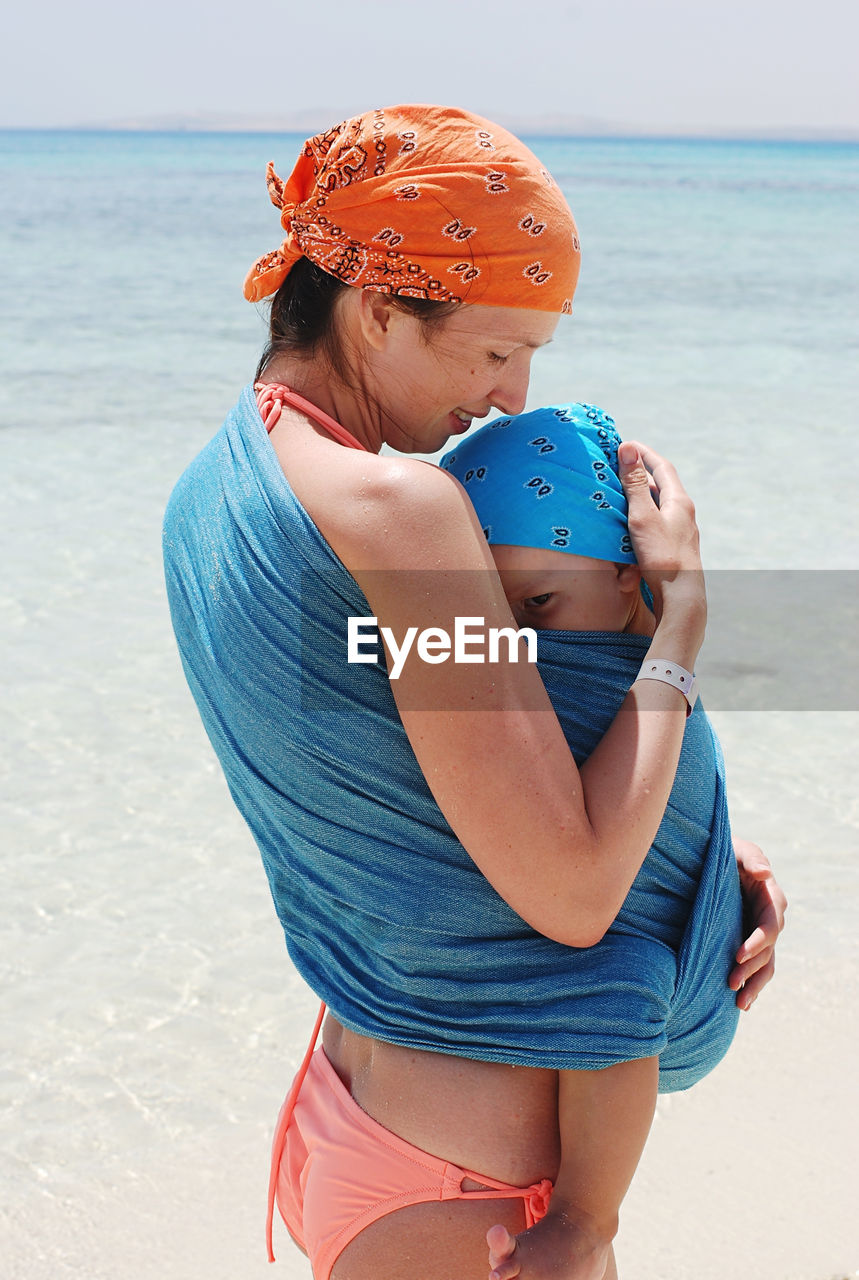 Rear view of woman holding her child at beach
