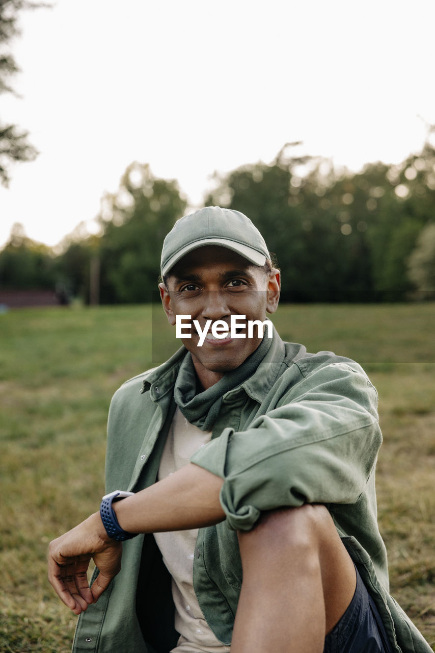 Portrait of happy man wearing cap while sitting in playground