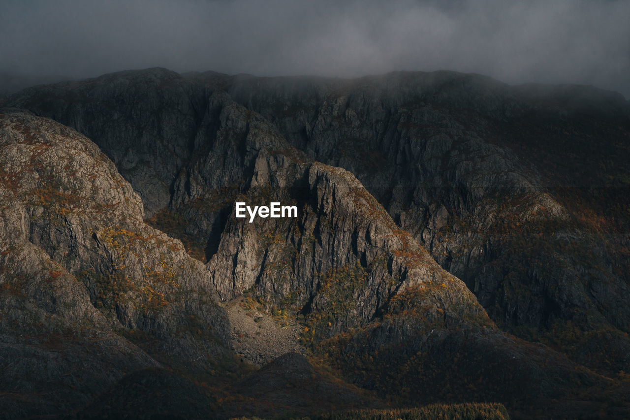 Scenic view of rocky mountains against misty sky