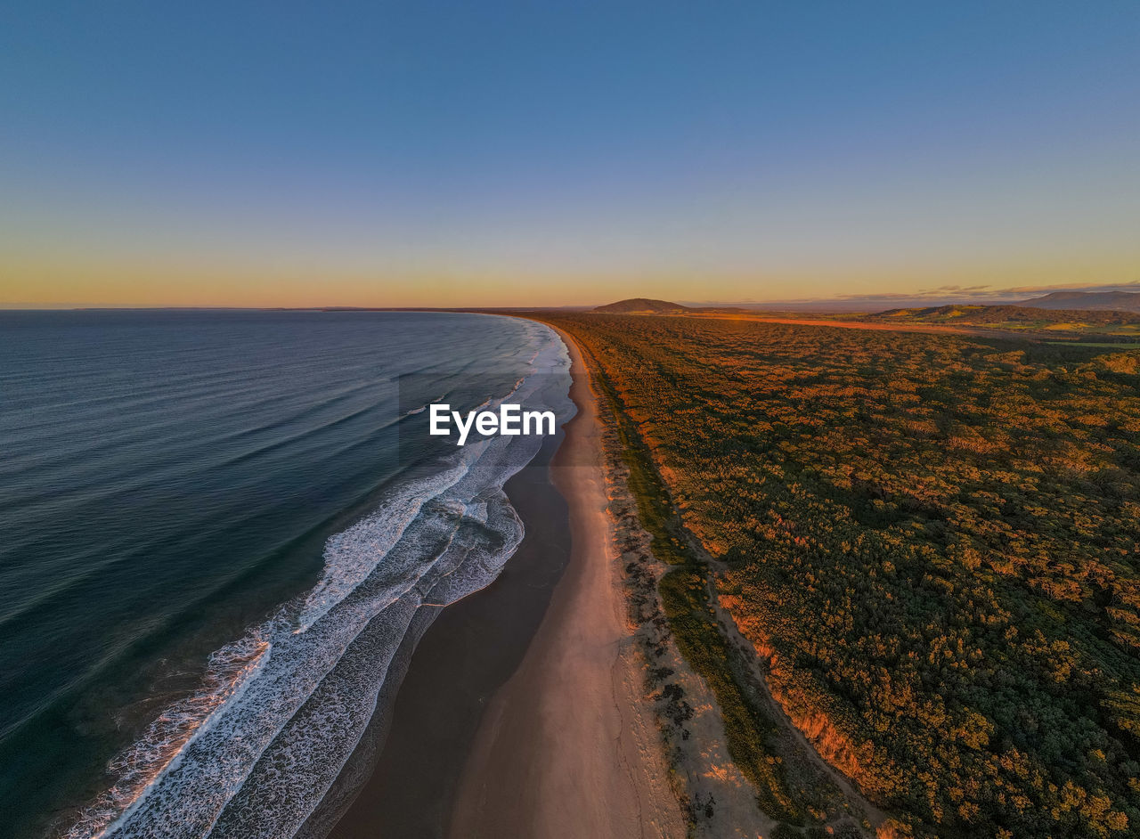Aerial view of sea against clear sky during sunset