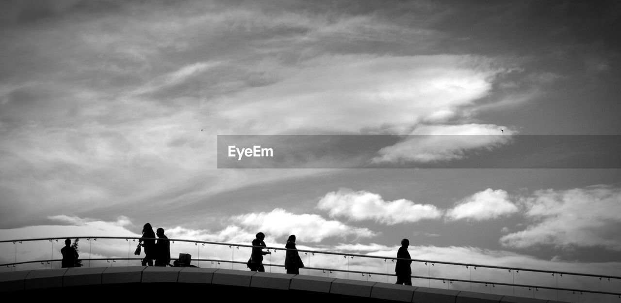 Low angle view of silhouette people walking on bridge