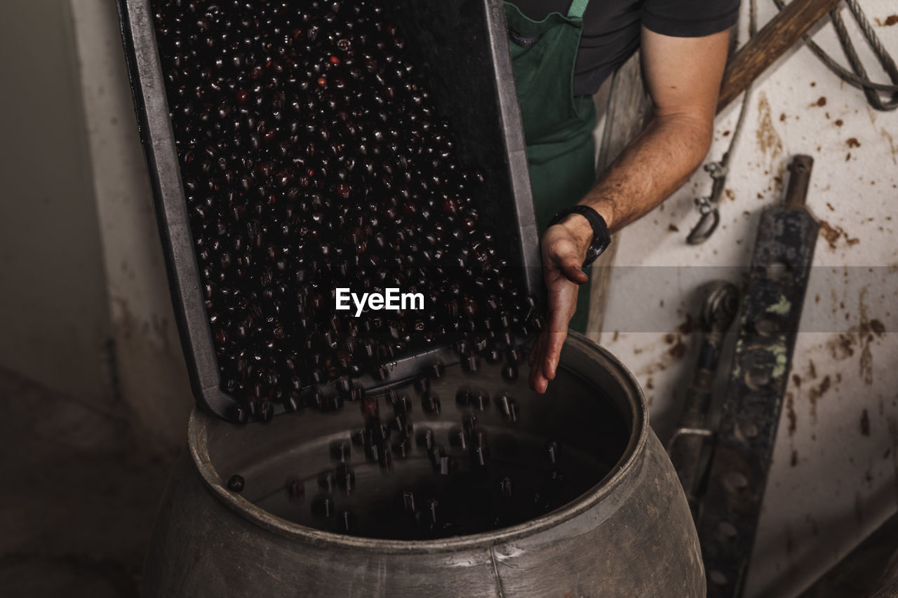 Man pouring harvested cherries into vessel