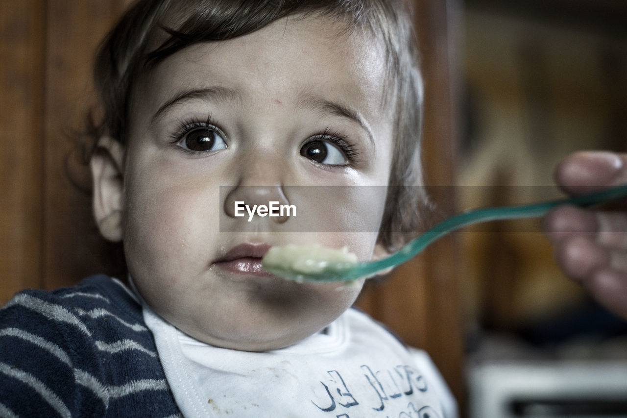 Cropped hand of parent feeding son at home