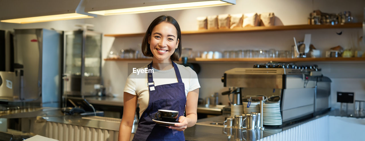 portrait of young woman standing in kitchen