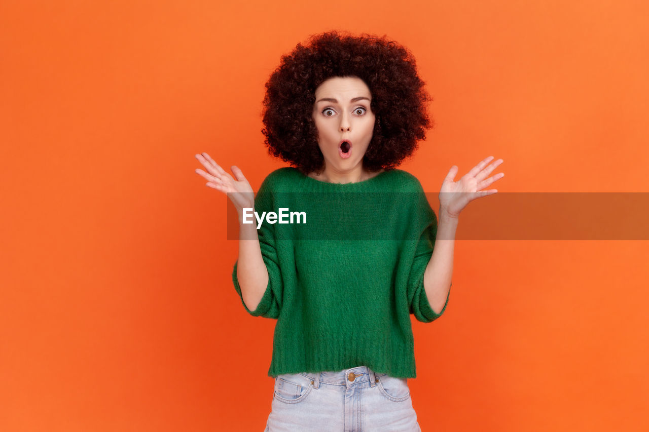 Surprised woman standing against colored background