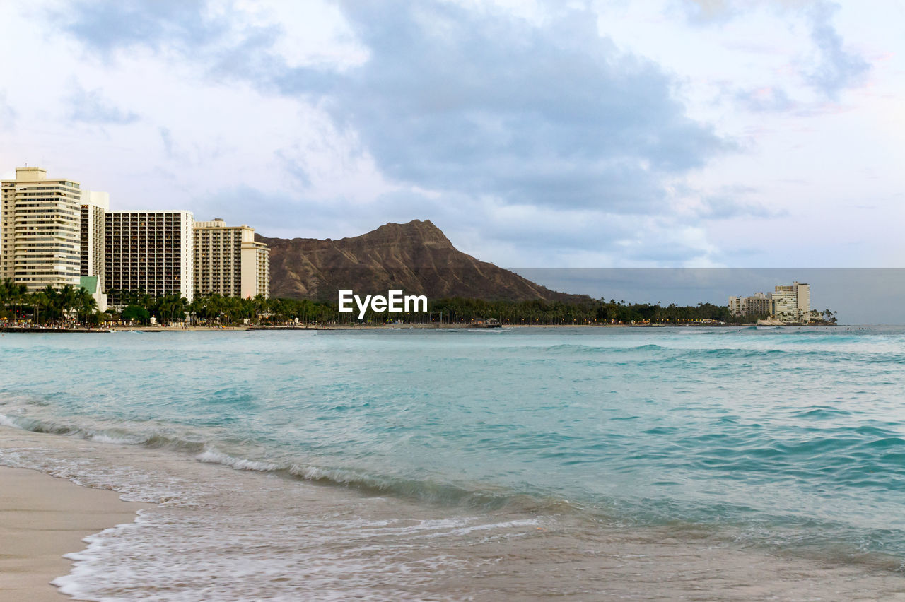 Scenic view of sea by buildings against sky