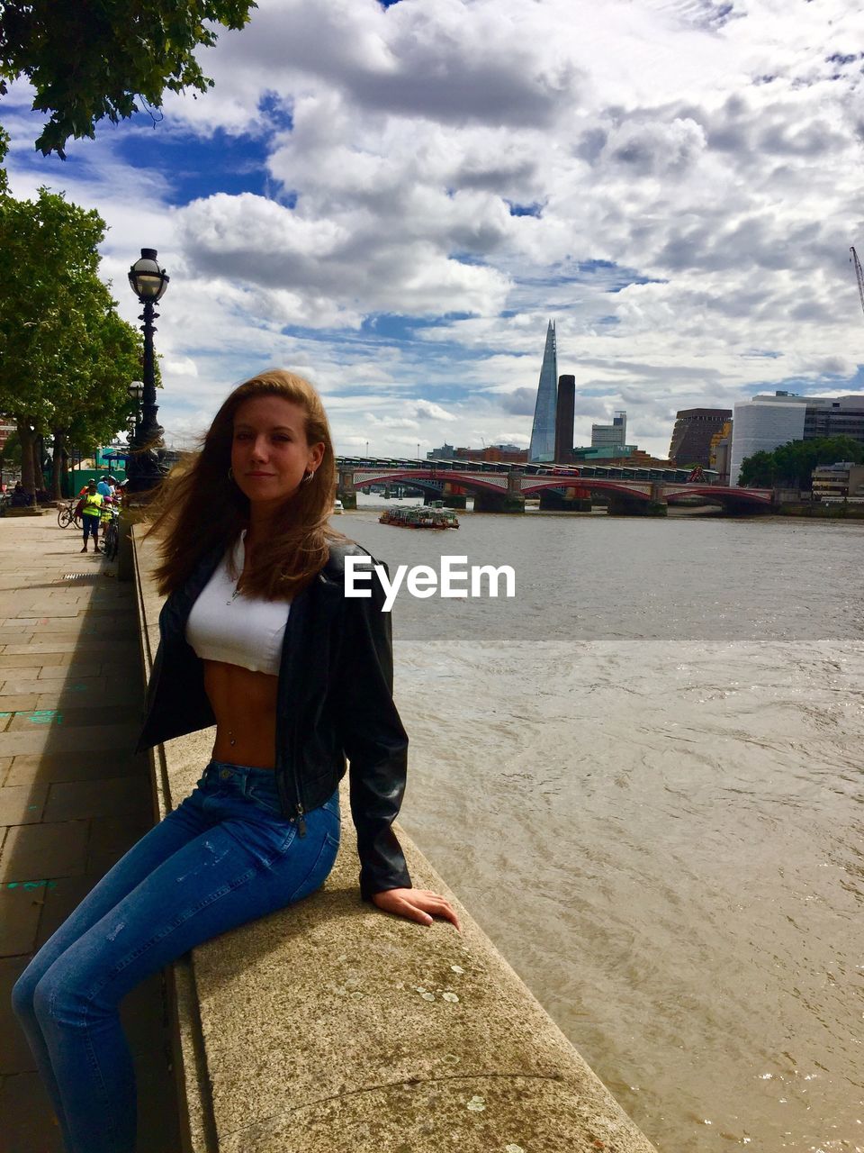 Portrait of girl sitting against river in city