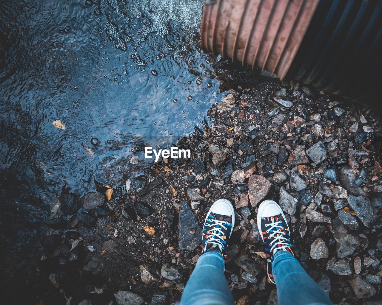 Low section of person standing on rocks by river 