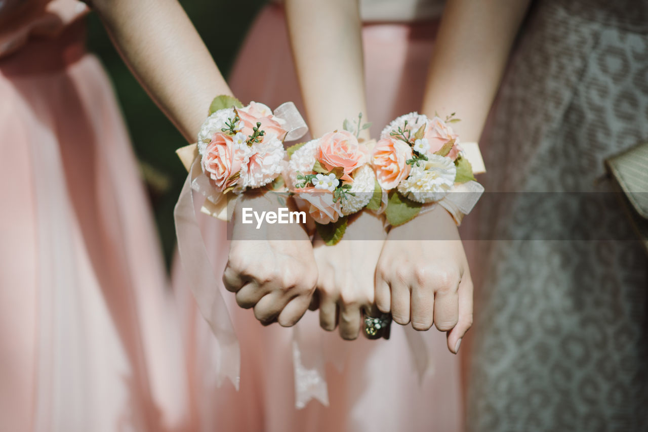 Midsection of bridesmaids showing flower bracelets in wedding ceremony